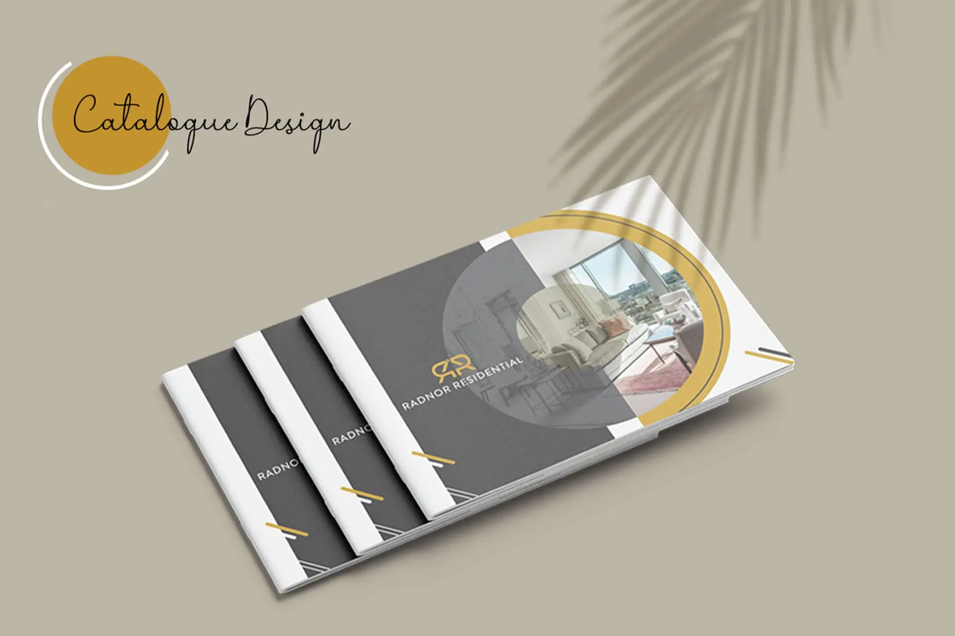 Radnor Residential Catalogue Design Mockup: A stack of modern, luxury residential property catalogues with a grey, white, and gold color scheme. The cover features a circular cutout showcasing a sleek living room interior. Real estate developer marketing, luxury home design portfolio, and high-end residential listings.